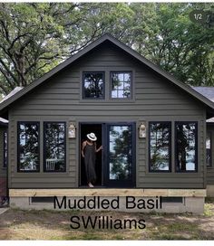 a woman standing in the open door of a small house with muddled basil swills