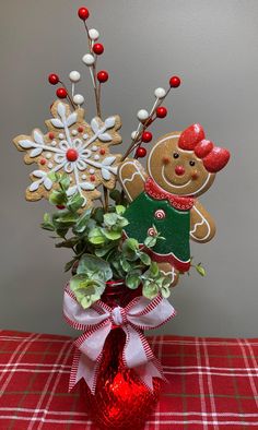 a vase filled with assorted holiday decorations on top of a red tablecloth covered table