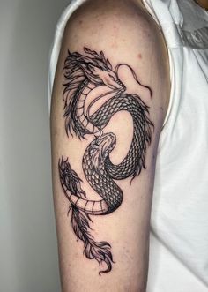 a man's arm with a dragon tattoo on the left side of his arm