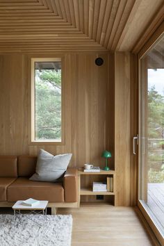 a living room with wood paneling and large windows on the side of the wall