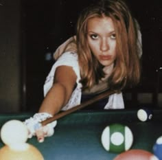 a woman leaning over a pool table with balls on it and a cue in her hand