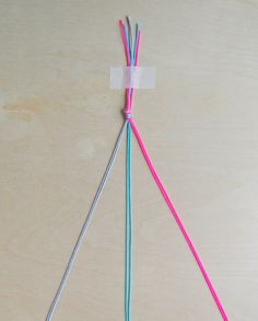 two pink and blue wires connected to each other on a wooden surface with a piece of plastic