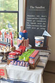 a table topped with lots of food next to a chalkboard sign that says the sandlot