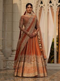 a woman in an orange and gold lehenga