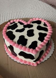 a heart shaped cake sitting on top of a cardboard box with pink and black icing