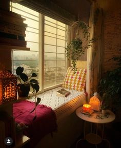 a bedroom with a window seat and plants on the windowsill, next to a small table