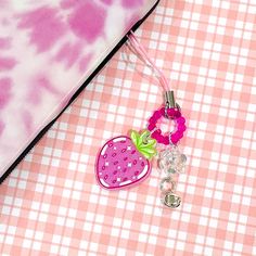 a pink and white tie dye pillow next to a strawberry key chain on a checkered table cloth