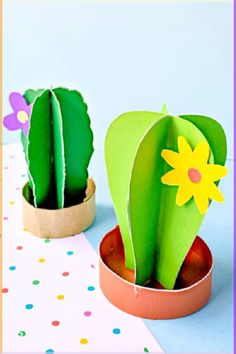 two paper flowers are in small pots on a table