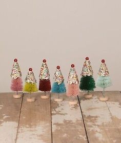 small plastic christmas trees with colorful pom poms on each one, set of 8