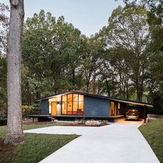 a modern house in the middle of a wooded area with trees and grass around it