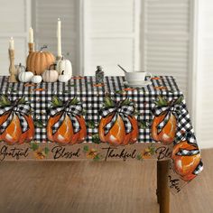 a table topped with an orange pumpkin covered in black and white checkered fabric next to candles