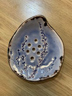 a blue and white dish with holes in the center on a wooden table, top view