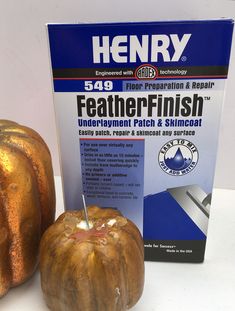 a golden pumpkin sitting next to a package of feathersfinish