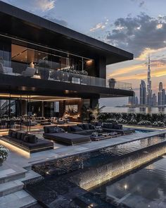 an outdoor living area with couches, tables and water features in front of the city skyline