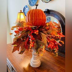 an arrangement of autumn leaves and pumpkins on a table in front of a mirror