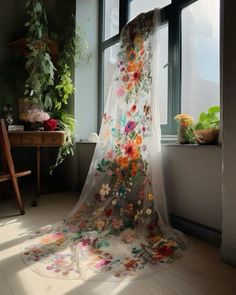 an open window with sheer curtains and flowers on it