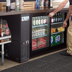 a man standing in front of a cooler filled with drinks