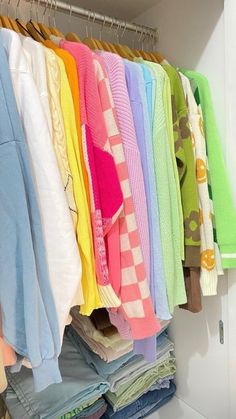 a closet filled with lots of different colored shirts