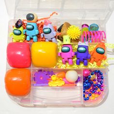 a plastic container filled with lots of toys and beads on top of a white table