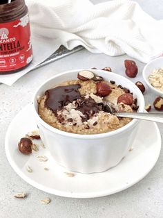 a bowl of oatmeal with nuts and chocolate in it on a plate