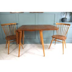 two wooden chairs and a table against a blue wall