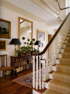 there is a staircase in the house with pictures on the wall and two lamps next to it