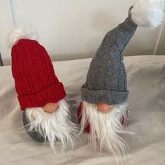 two knitted gnomes with white hair and beards on top of a bed