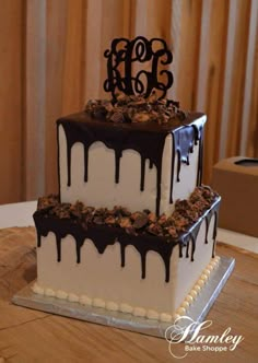 a three tiered cake with chocolate drizzles and the letter e on top