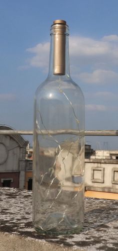 a glass bottle with water in it sitting on top of a cement slab next to a building