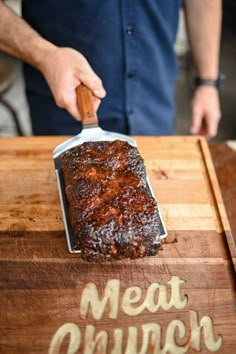 a person cutting meat on top of a wooden cutting board with a knife in it