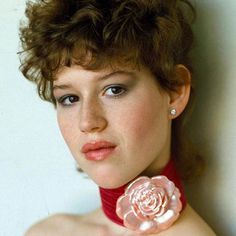 a close up of a person wearing a red choker and a rose brooch