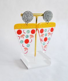 a pair of earrings that are sitting on a stand