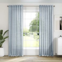 a living room with a large window covered in blue curtains and a potted plant