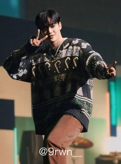 a young man standing on top of a stage giving the peace sign with his hand