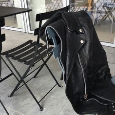 a black leather jacket sitting on top of a folding chair