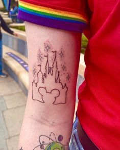 a person with a tattoo on their arm that has a castle and rainbows in the background