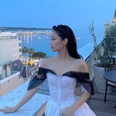 a woman in a white dress standing on a balcony