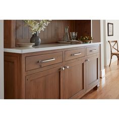 a kitchen with wooden cabinets and white counter tops, along with a vase filled with flowers