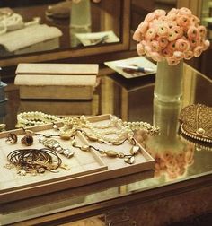 a glass table topped with jewelry and a vase filled with flowers