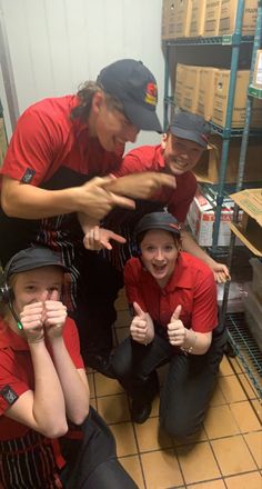 three women in red shirts and black pants posing for the camera with their thumbs up