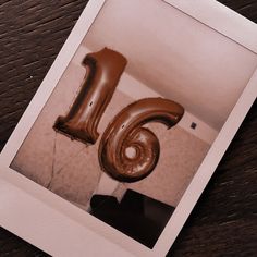 the number sixteen balloon is in the shape of a giant letter on top of a wooden table