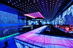 the bar is lit up with colorful lights and decorated with blue, pink, and purple colors