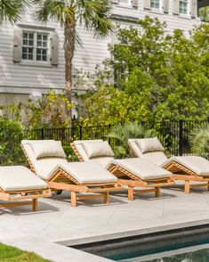 four chaise lounge chairs sitting next to a swimming pool