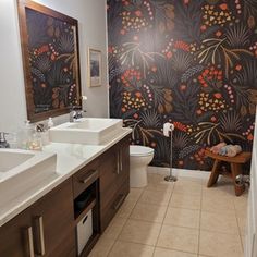 a bathroom with two sinks and a large floral wallpaper