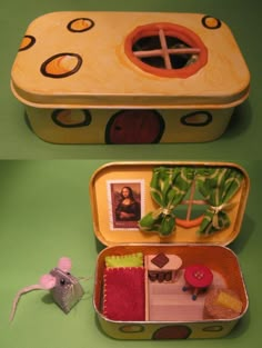 two tins with pictures in them on a green surface and one has a toy mouse