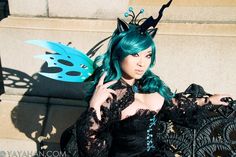 a woman with green hair wearing a black dress and butterfly wings on top of her head