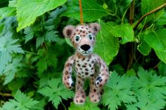 a stuffed animal that is hanging from a tree with green leaves in front of it