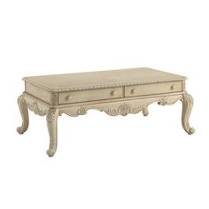 an antique white coffee table with drawers