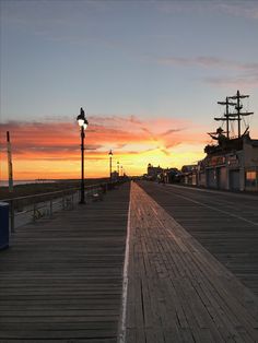 the sun is setting over an empty boardwalk