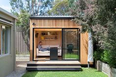 a person sitting on a couch in a small backyard area with sliding glass doors to the outside